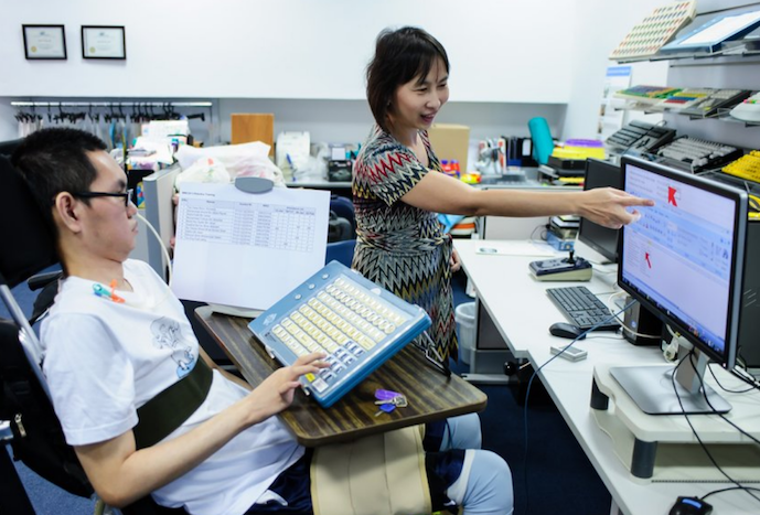 Woman shows young man how to navigate web using assistive device