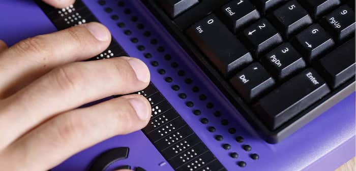 Male hand navigates website using braille keyboard