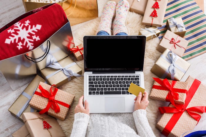 woman with computer and credit card surrounded by gifts