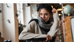 Woman sitting in antique store looking into camera wearing Olive Clothing